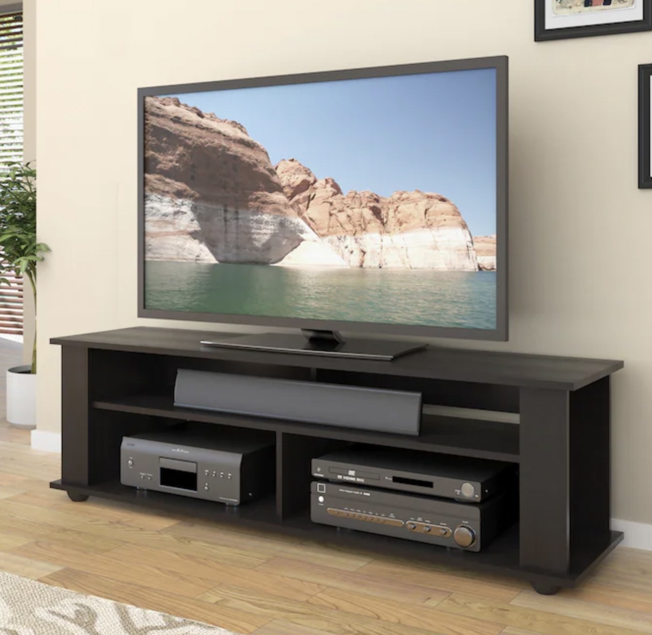 Black Ravenwood television stand with full length sound bar shelf propped against wall