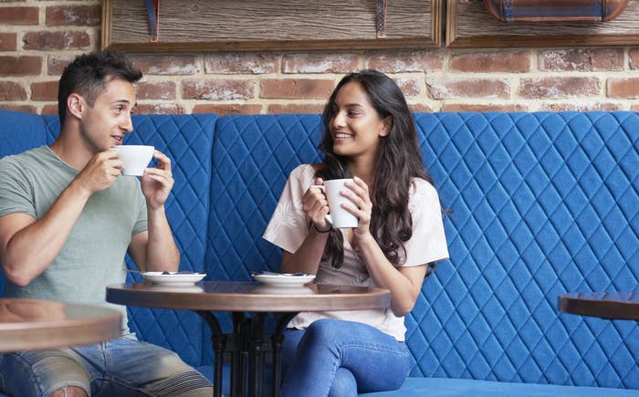 A man and a woman are sitting together and talking in a coffee shop.