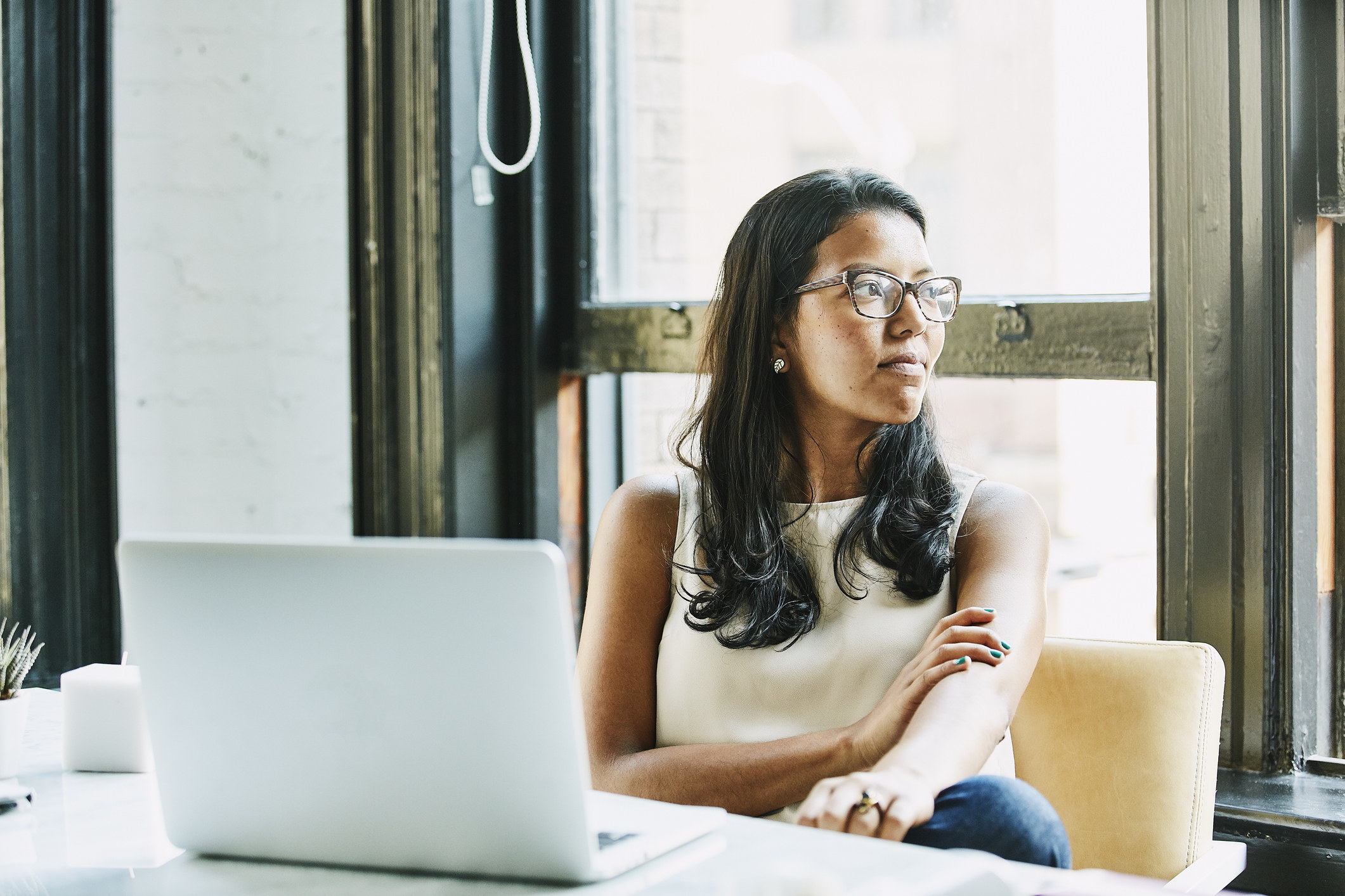 A woman sits at her computer, lost in thought.