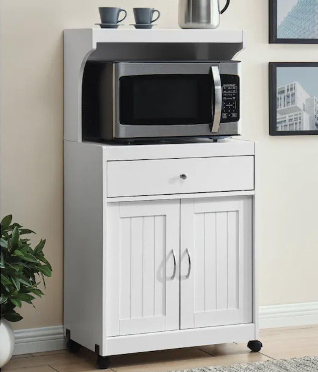 White wooden microwaveable cart with cabinets, shelves and a microwave on top