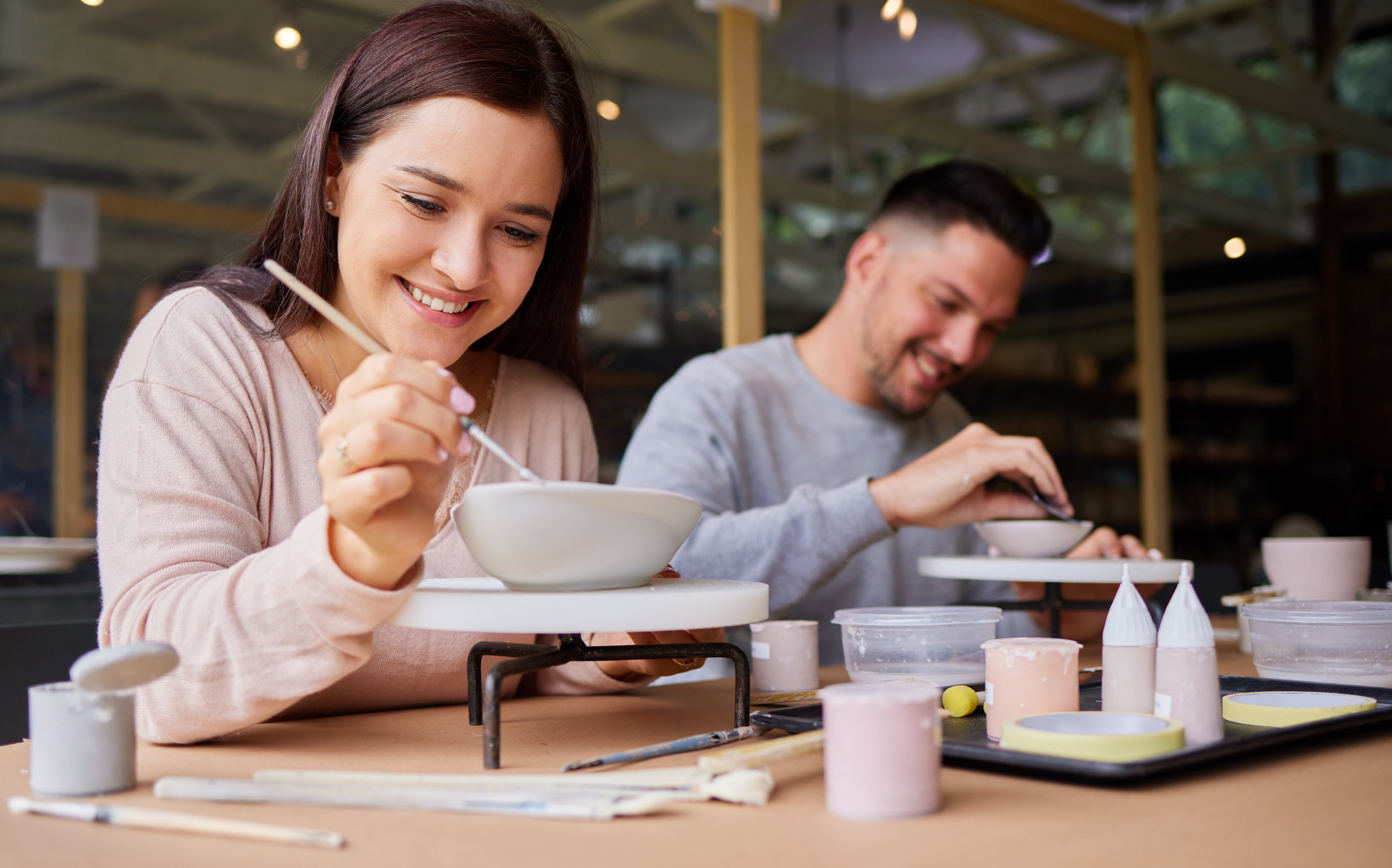A man and a women are painting pottery together.