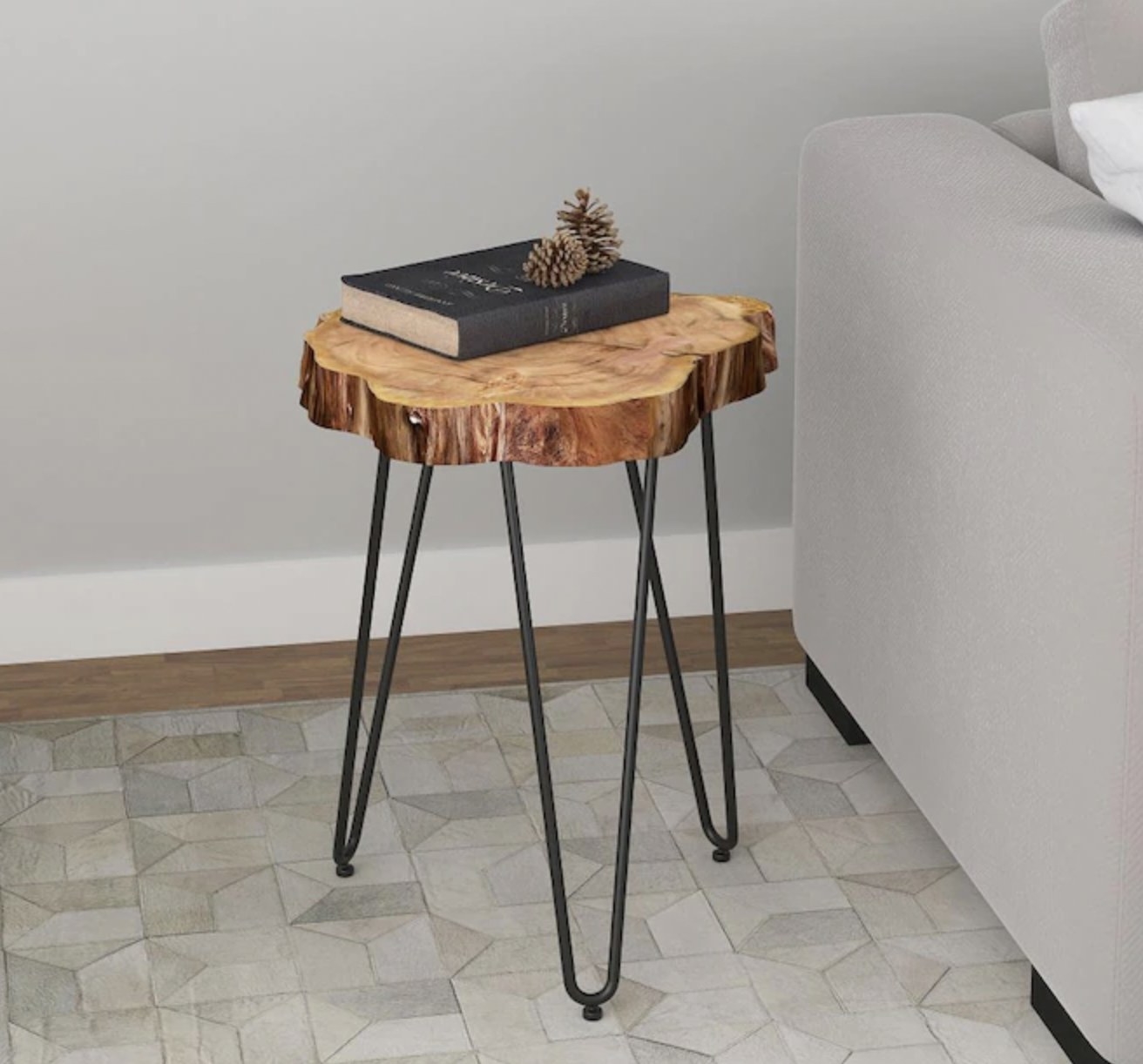 Wooden end table with steel legs next to a couch with a book on top