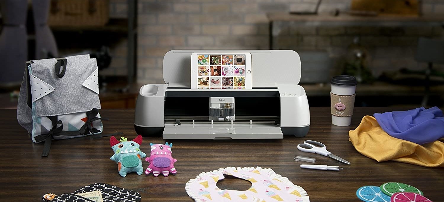 the white Cricut maker on a desk with crafty things