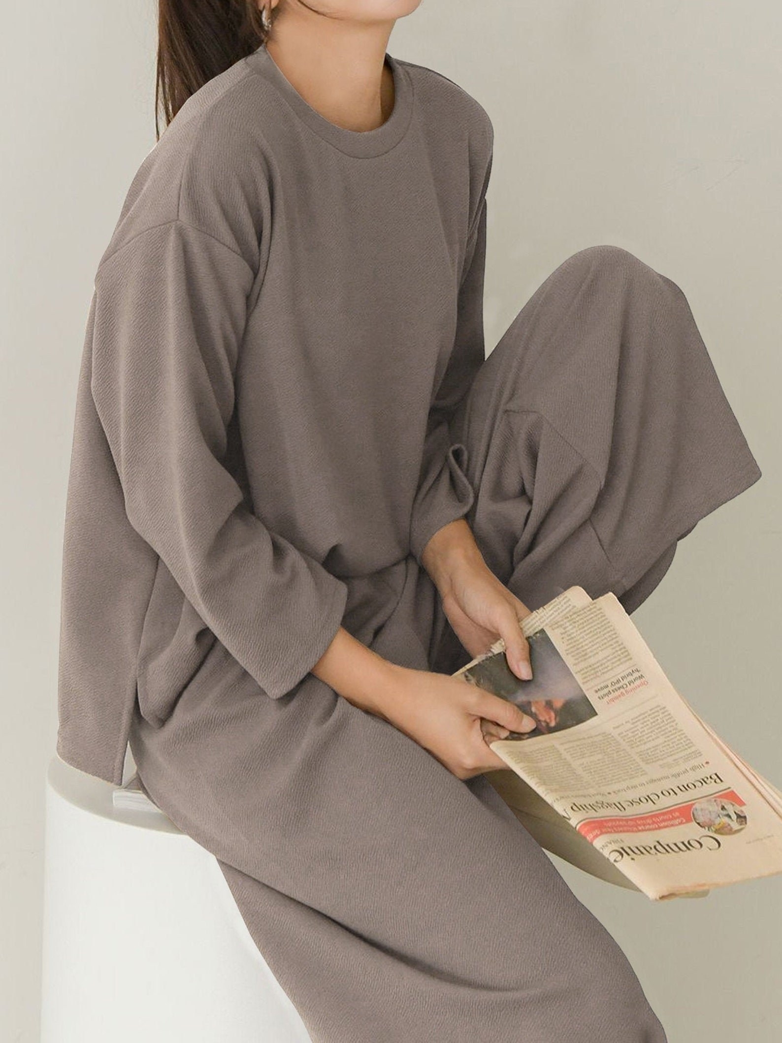 A model wearing the set in gray while reading a book
