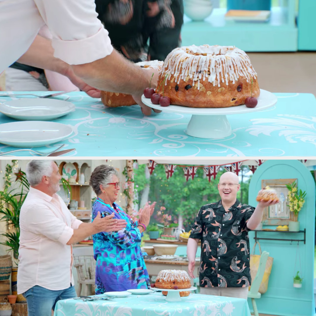 Matt holding the cake above his head while Paul and Prue applaud