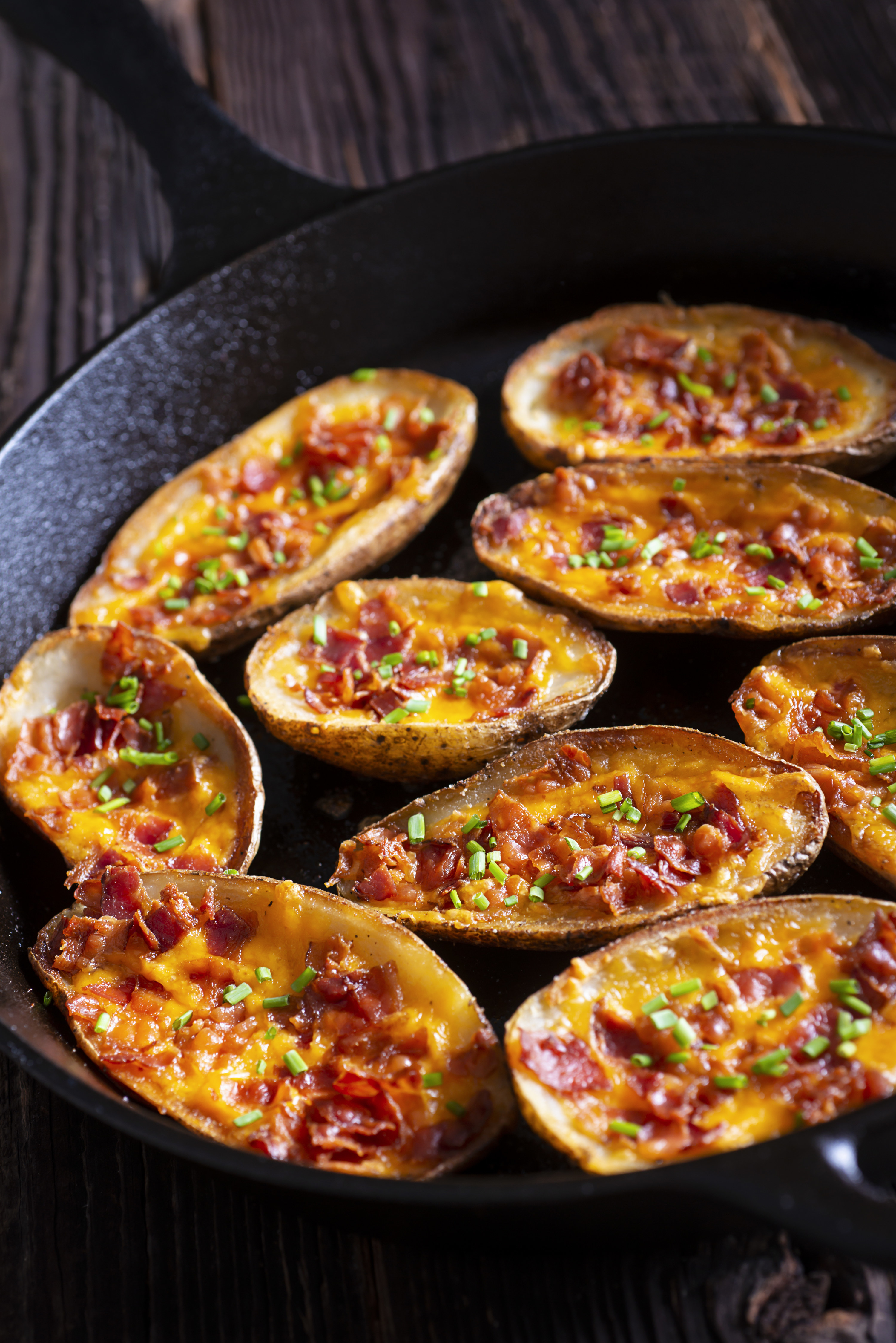potato skins with cheese and bacon in a cast iron skillet