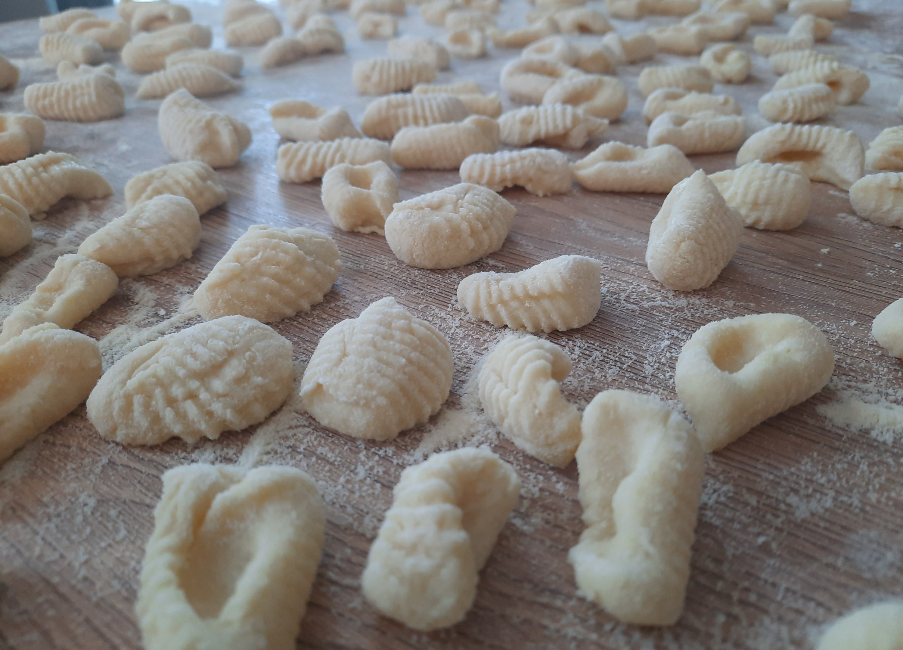 homemade gnocchi, uncooked, on a wooden cutting board