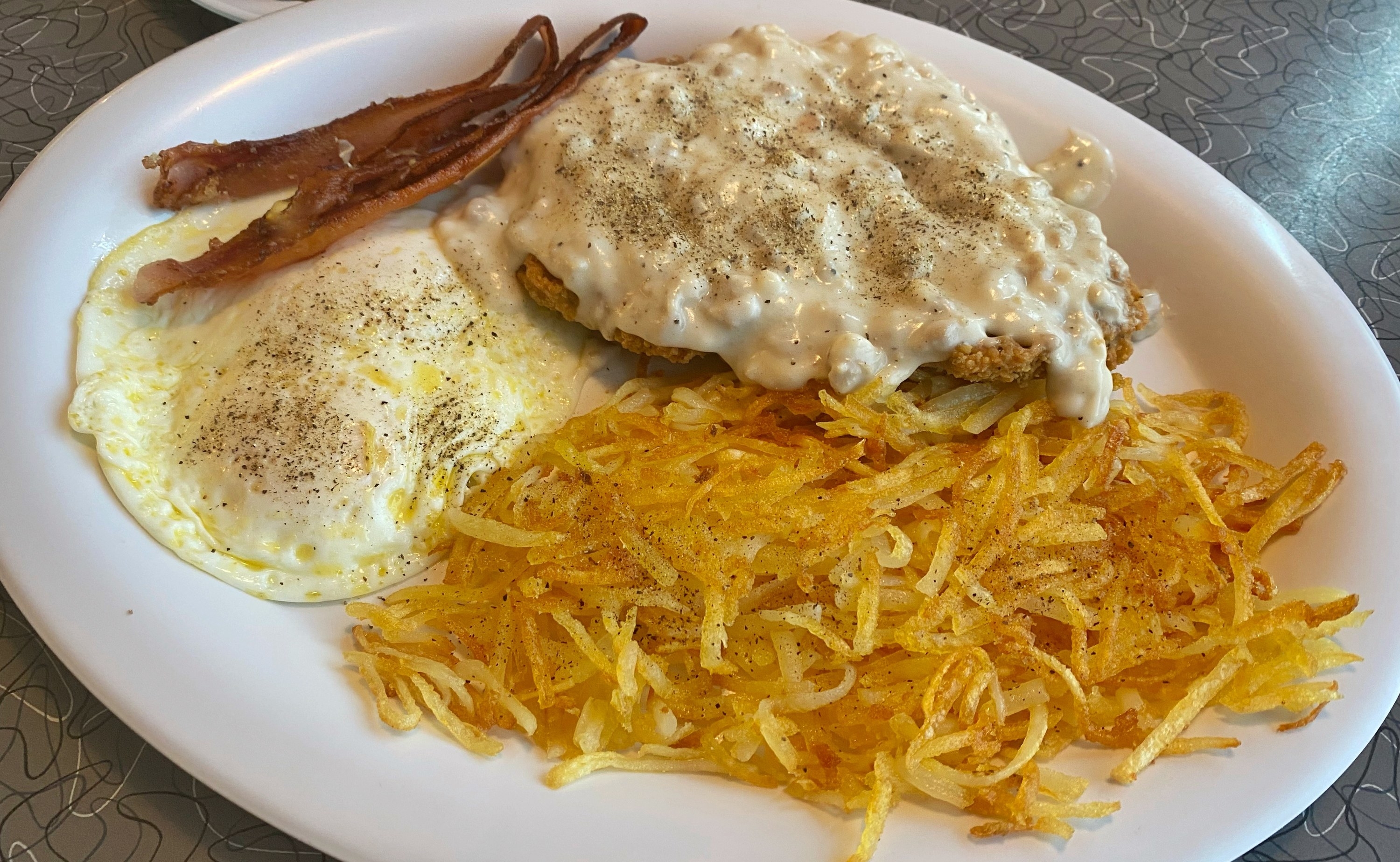 hash browns on a plate with eggs and bacon