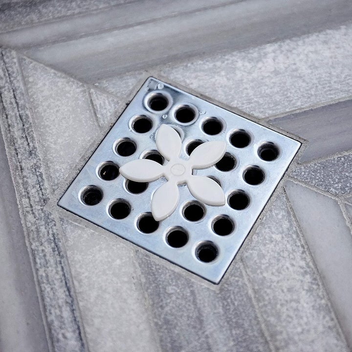 the flower shaped top of the strainer nestled on a shower drain