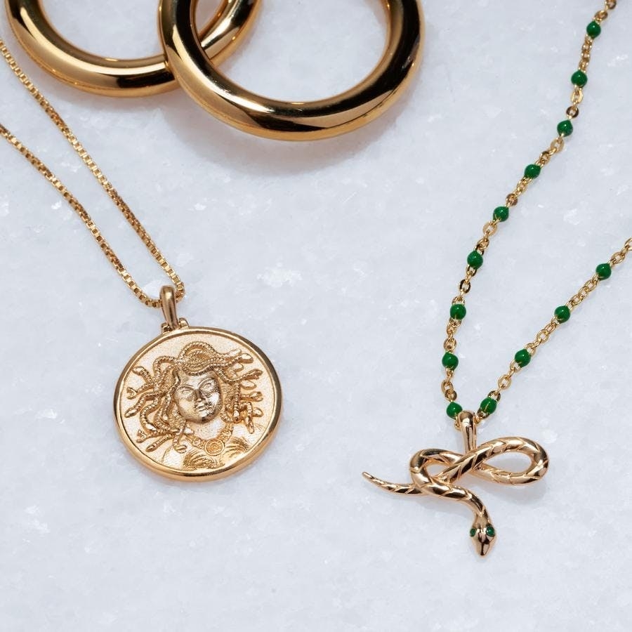 a gold coin necklace with medusa on it