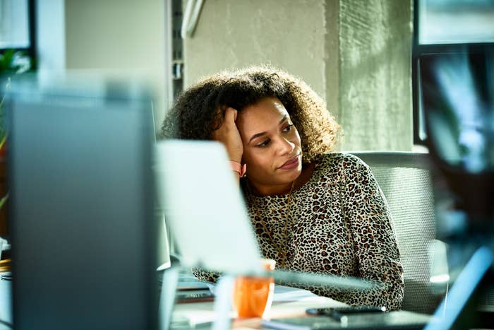 A woman sitting at her desk with her hand on her head