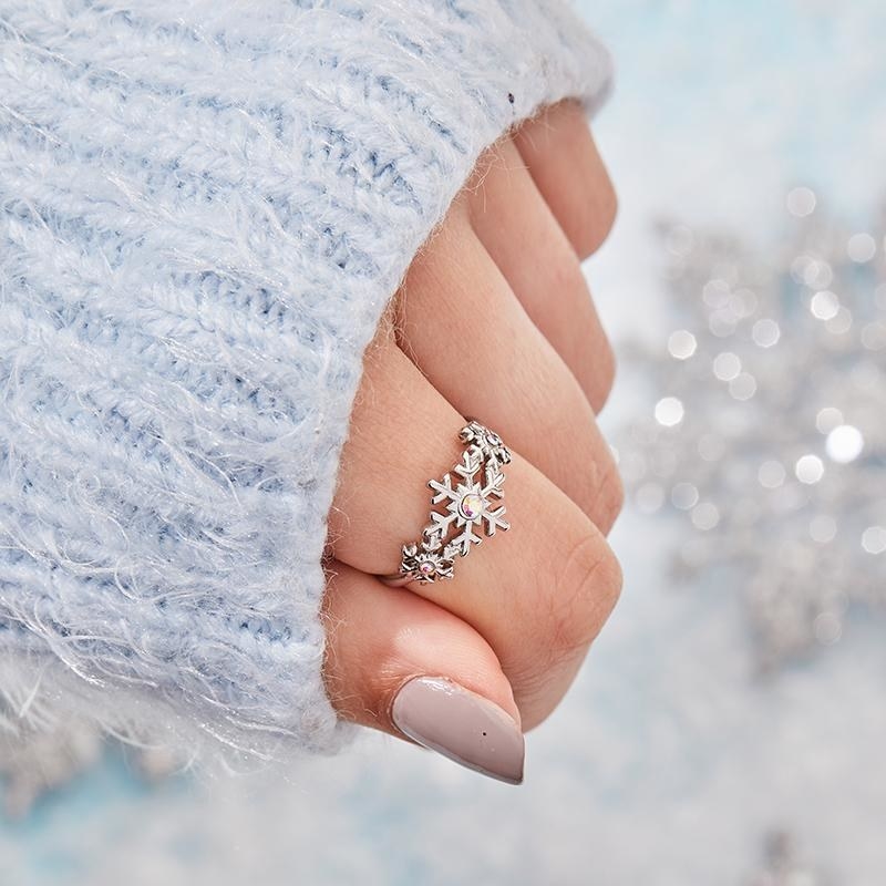 a model wearing a silver ring with one big snowflake in the middle and two smaller one on each side