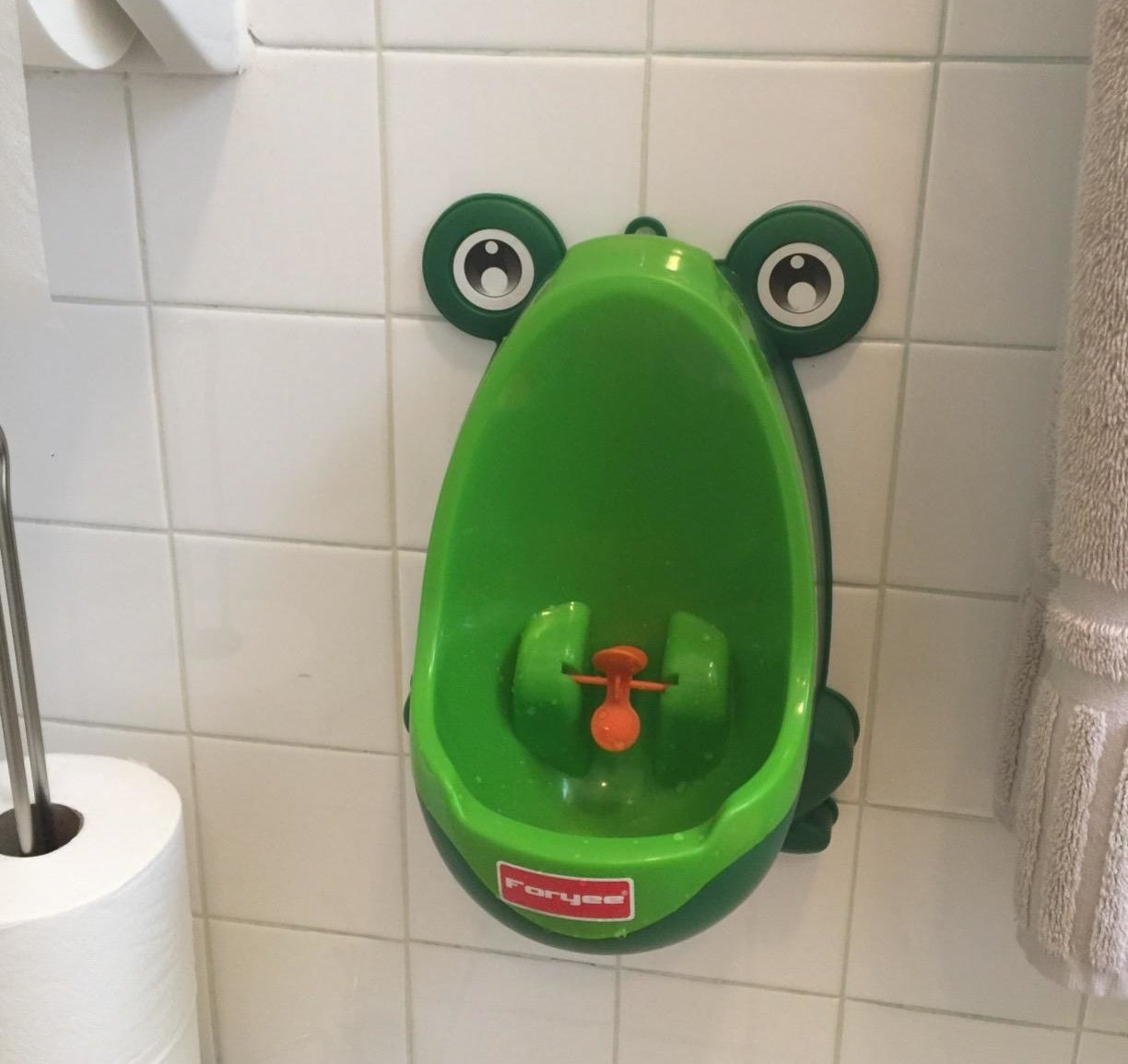 Reviewer&#x27;s photo showing the green urinal hanging on a tile wall