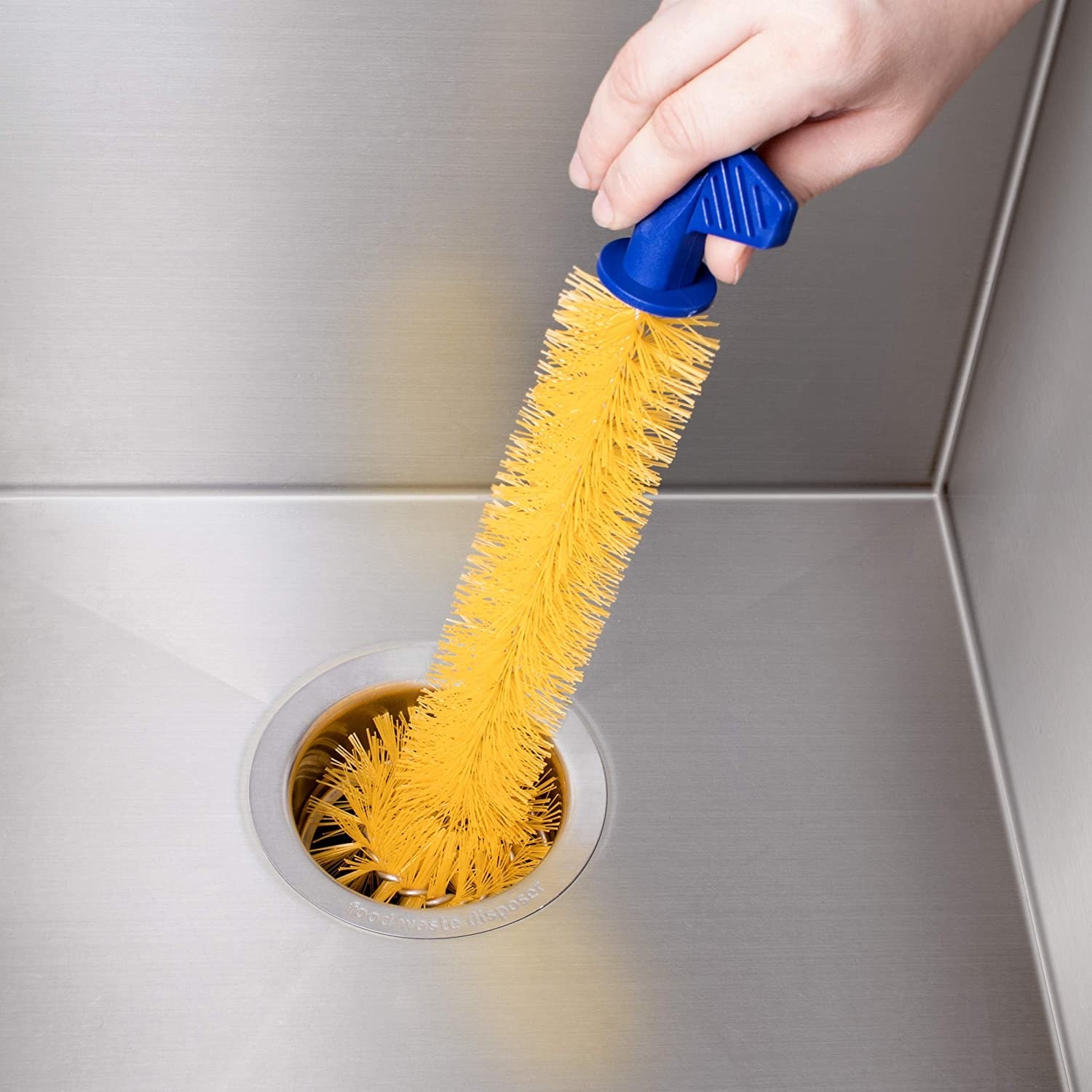 someone inserting the long garburator brush into a sink drain