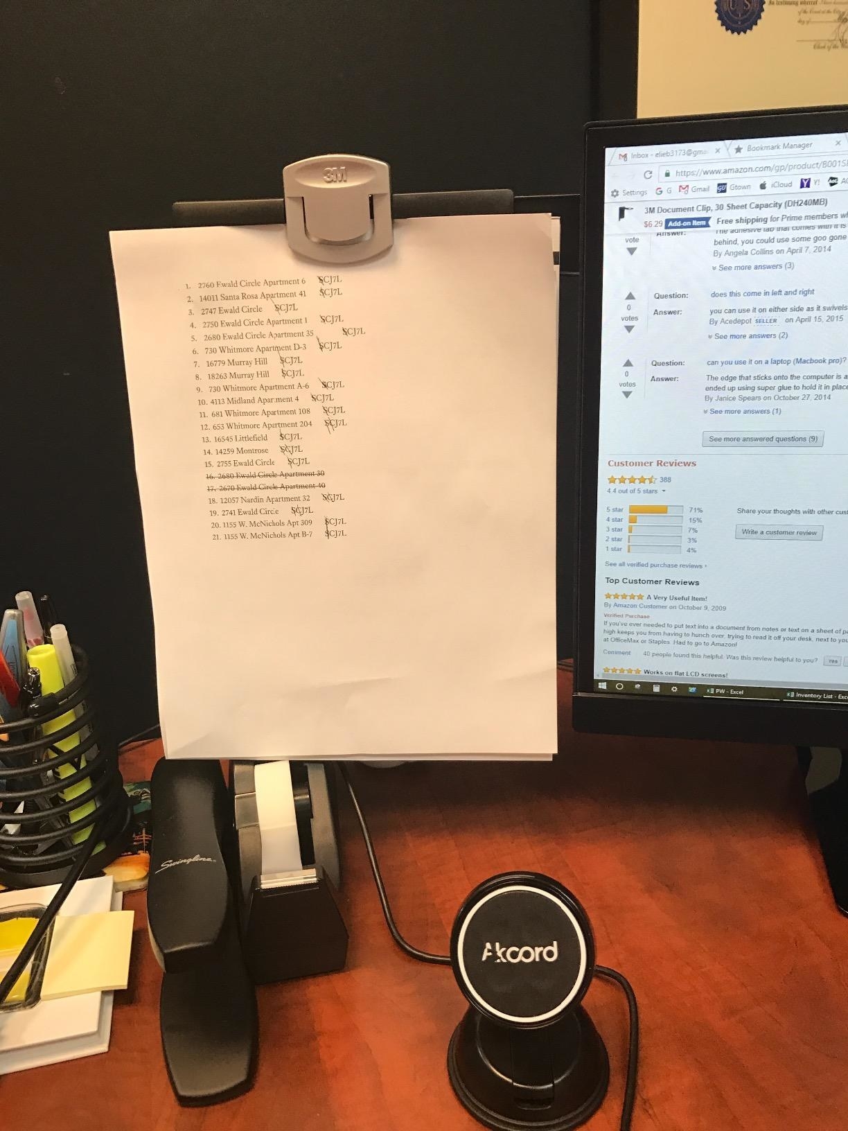 black and gray clip holding papers right alongside reviewer&#x27;s monitor