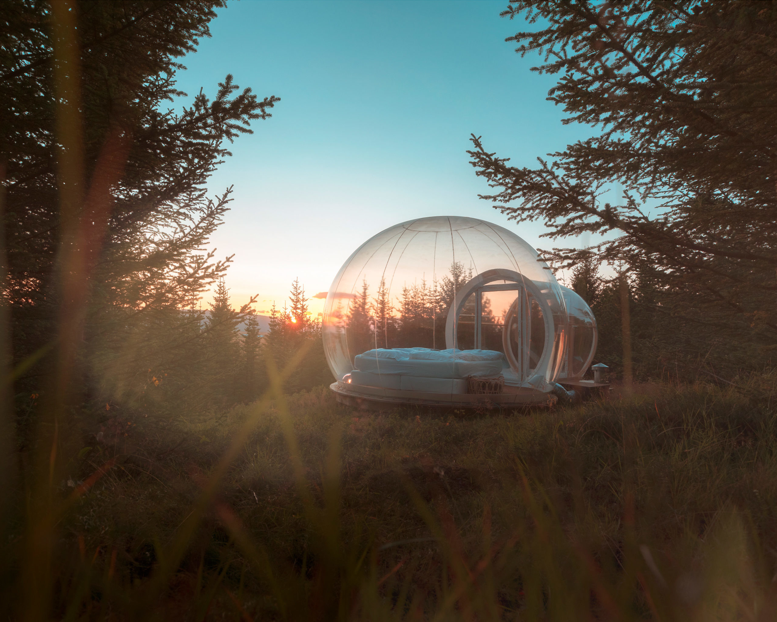 a clear bubble sleeping dome with bed underneath the open Iceland skies perfect for watching the northern lights