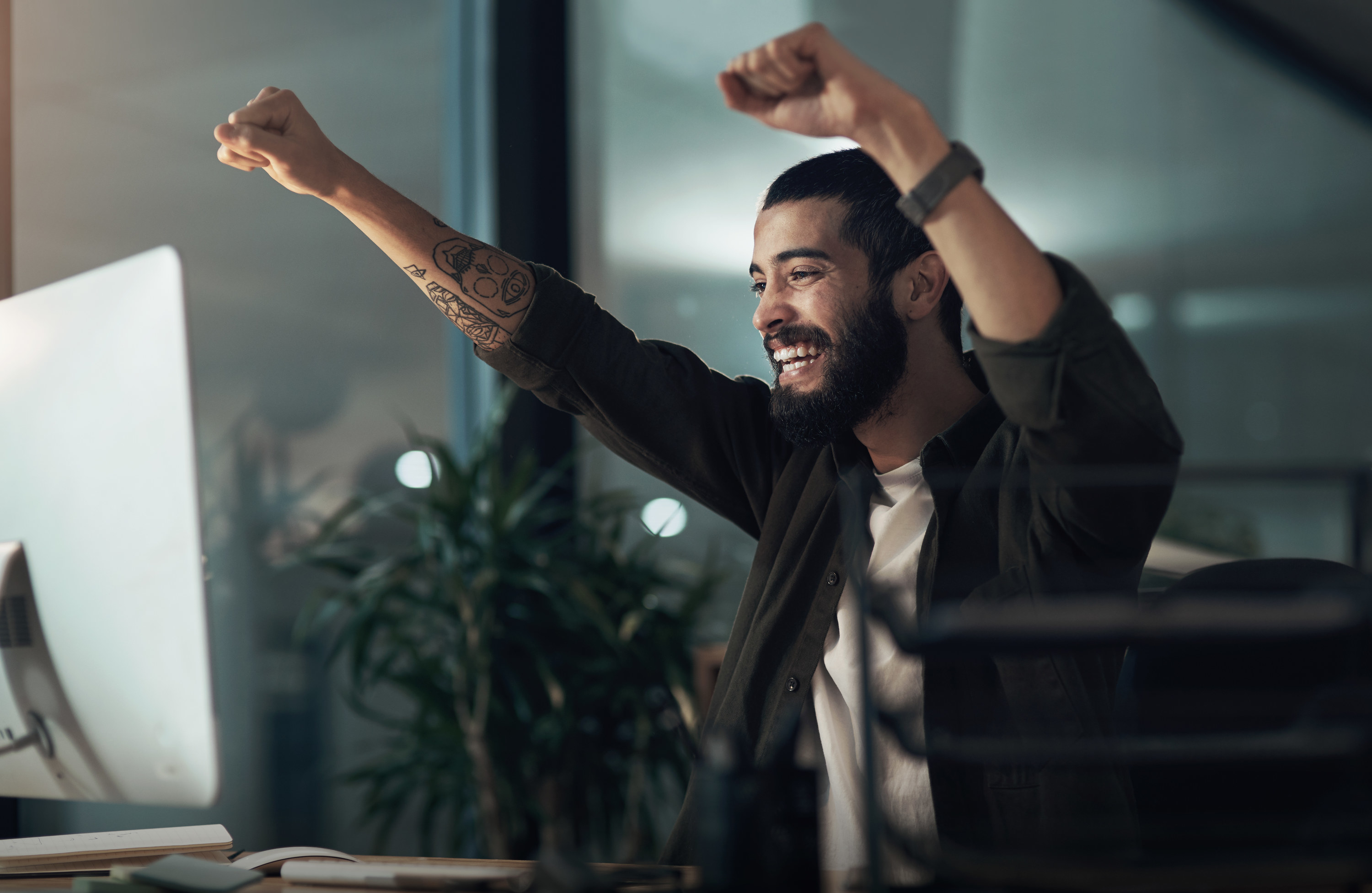 Man cheering at his desk after getting a raise or bonus