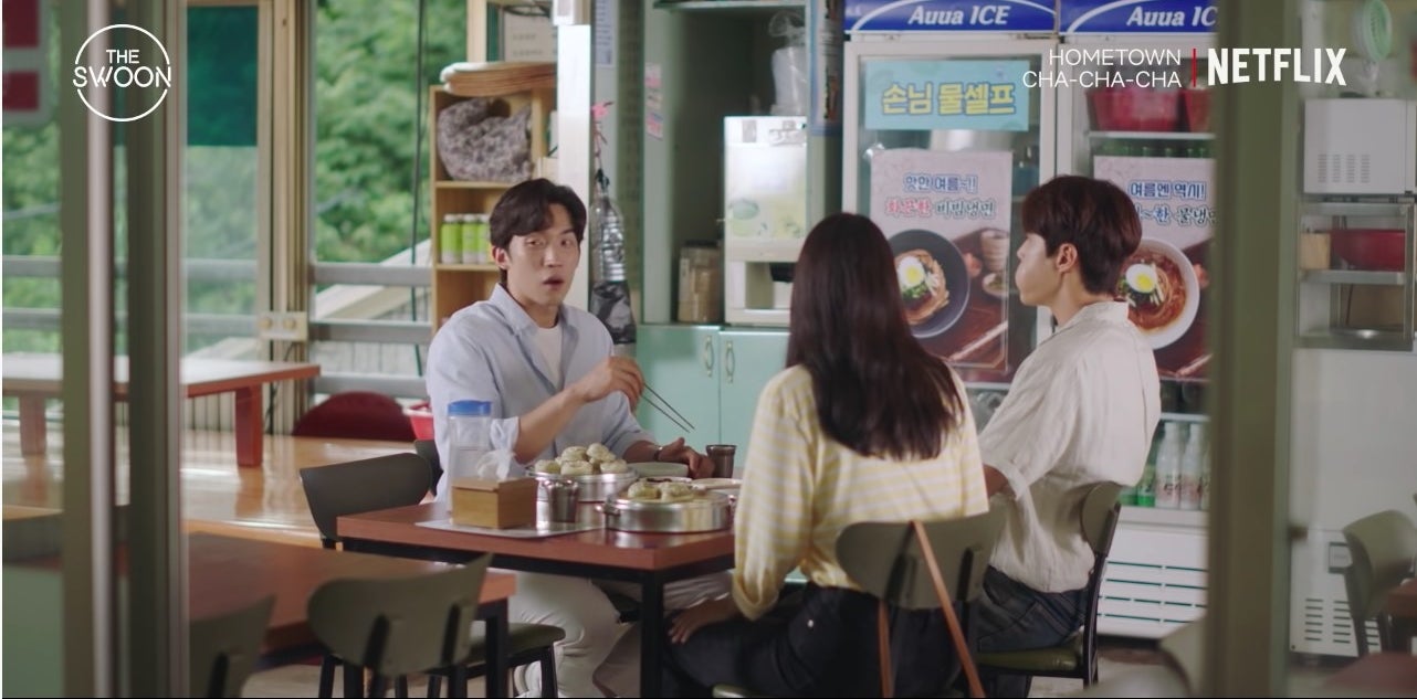 Two men and one woman eating at a restaurant.