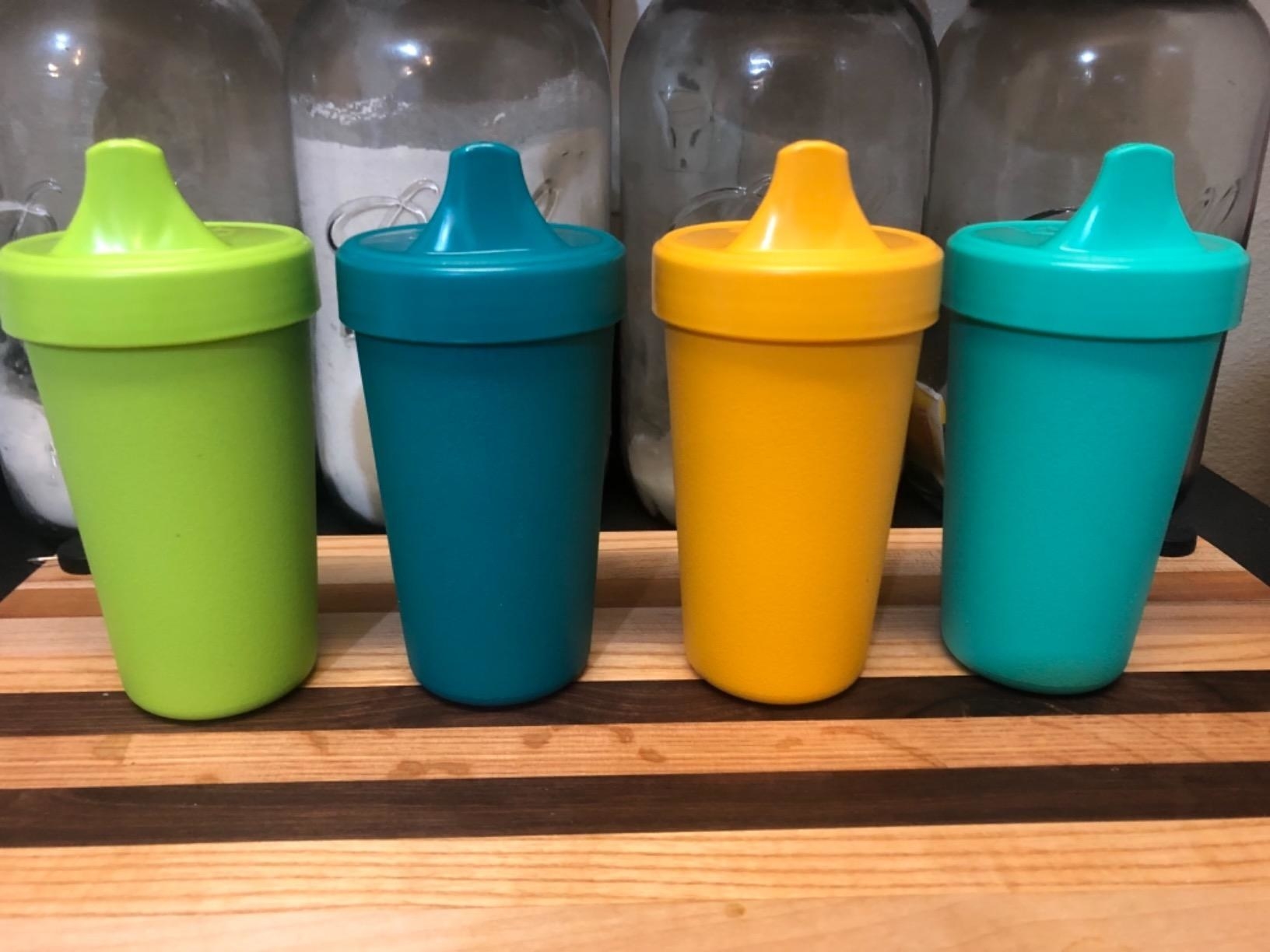 Reviewer&#x27;s photo of the cups in green, teal, yellow, and aqua