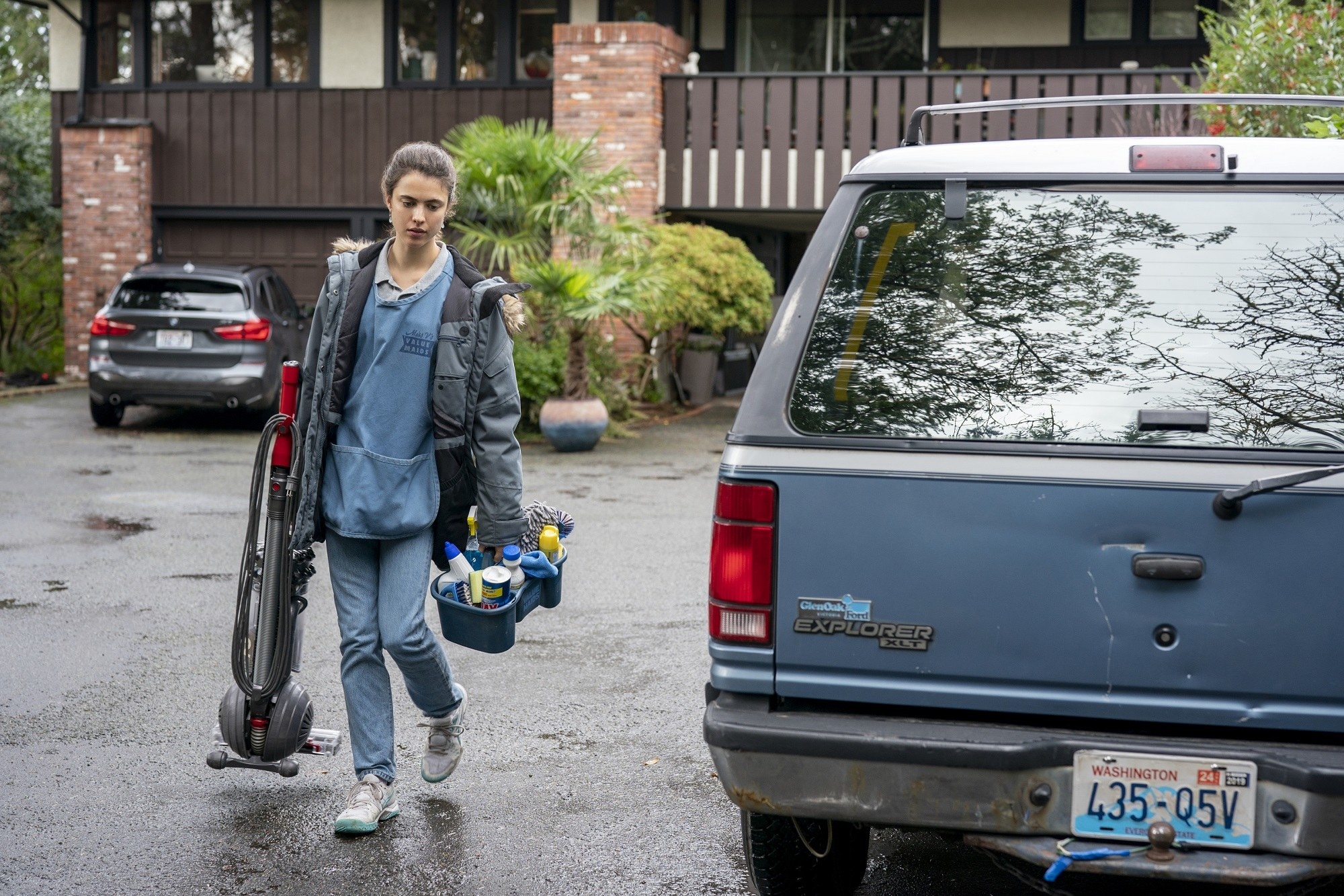 Alex carries cleaning equipment to her car in the Netflix series &quot;Maid&quot;