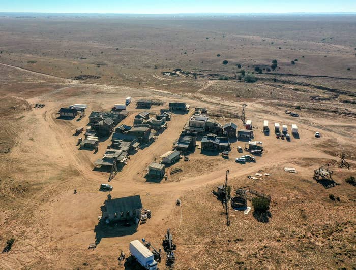 A compound with buildings and vehicles in the middle of a sparse environment