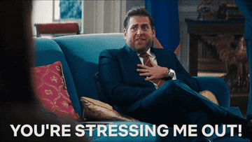 Jonah Hill sit on a blue sofa, in a clue suit touching his hand to his chest saying &quot;you&#x27;re stressing me out&quot;