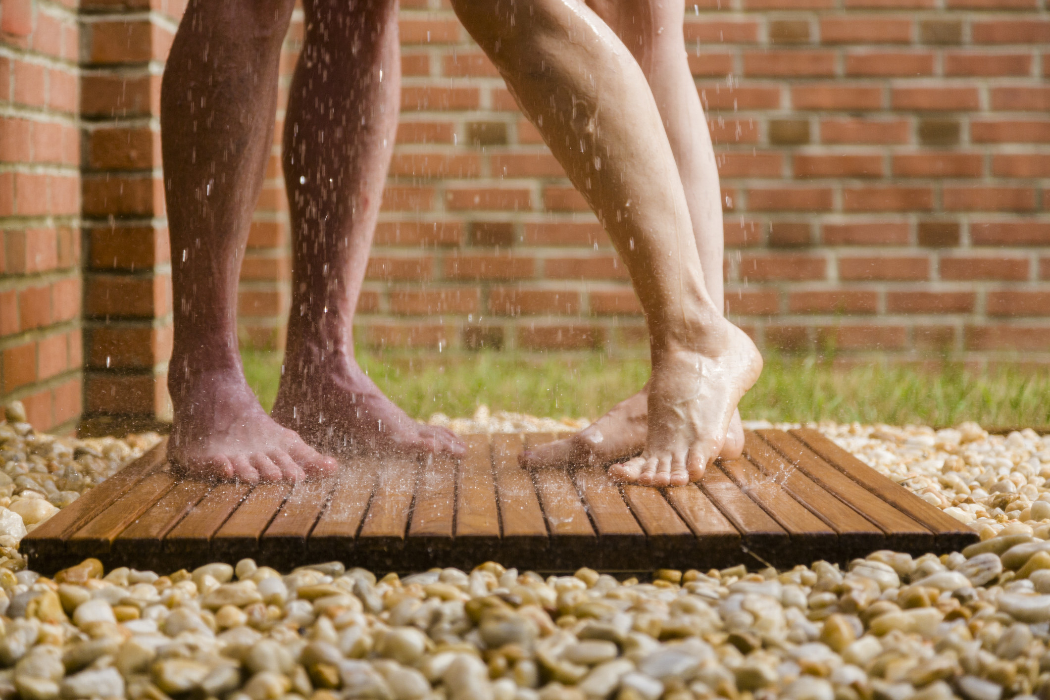 A closeup of the feet of two people taking a shower together