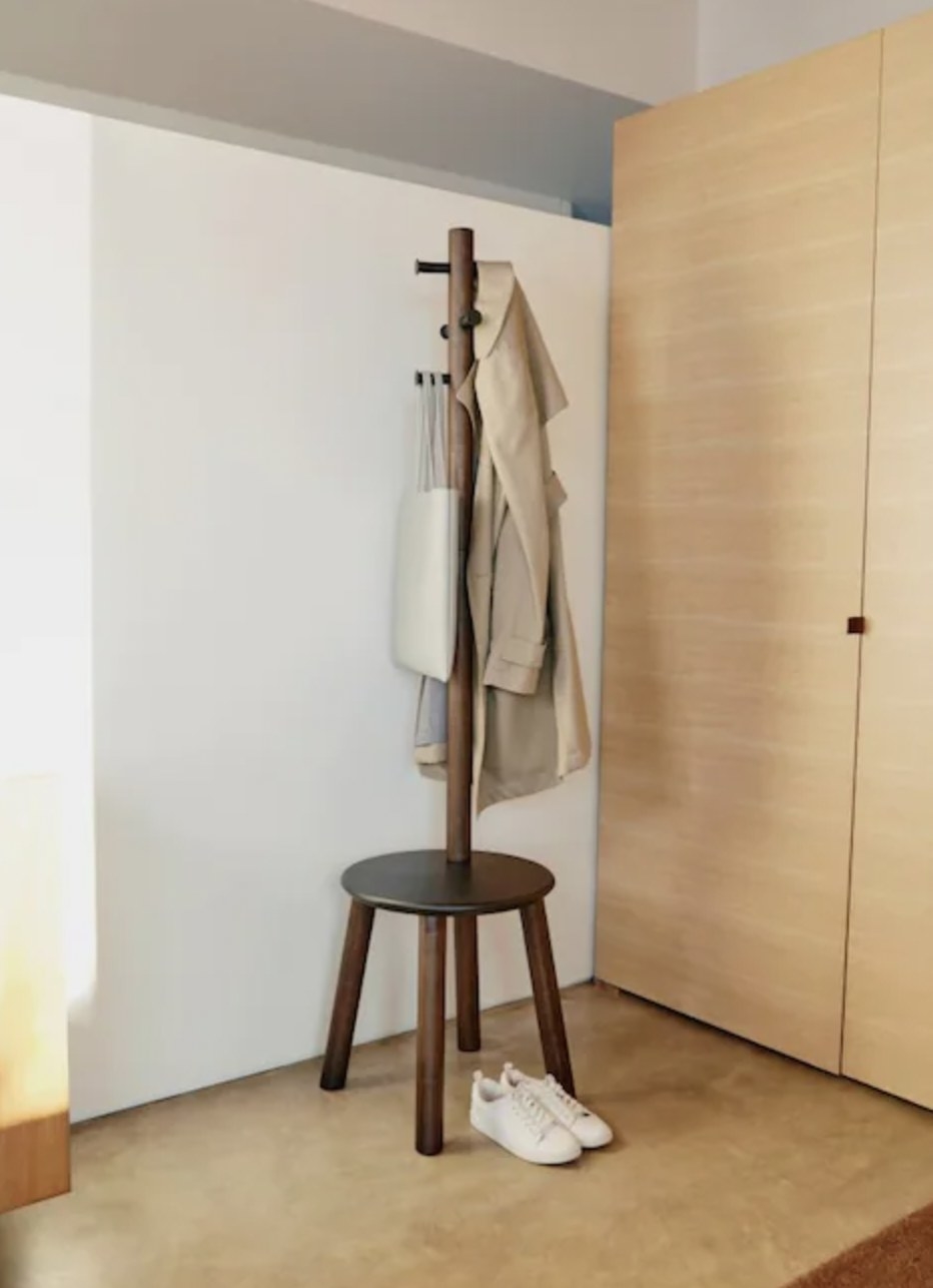 Umbrella pillar and coat rack by a pair of sneakers and a coat