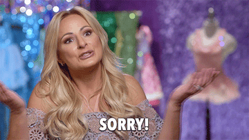 Blonde woman in an off the shoulder top, hands out to the side saying &quot;I&#x27;m sorry&quot;.