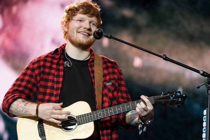 Ed at a microphone playing guitar and smiling