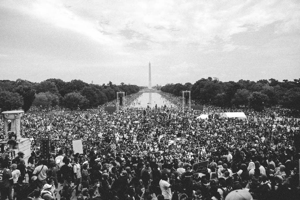 A huge group of protestors at the washington mall with the washington monument in the distance