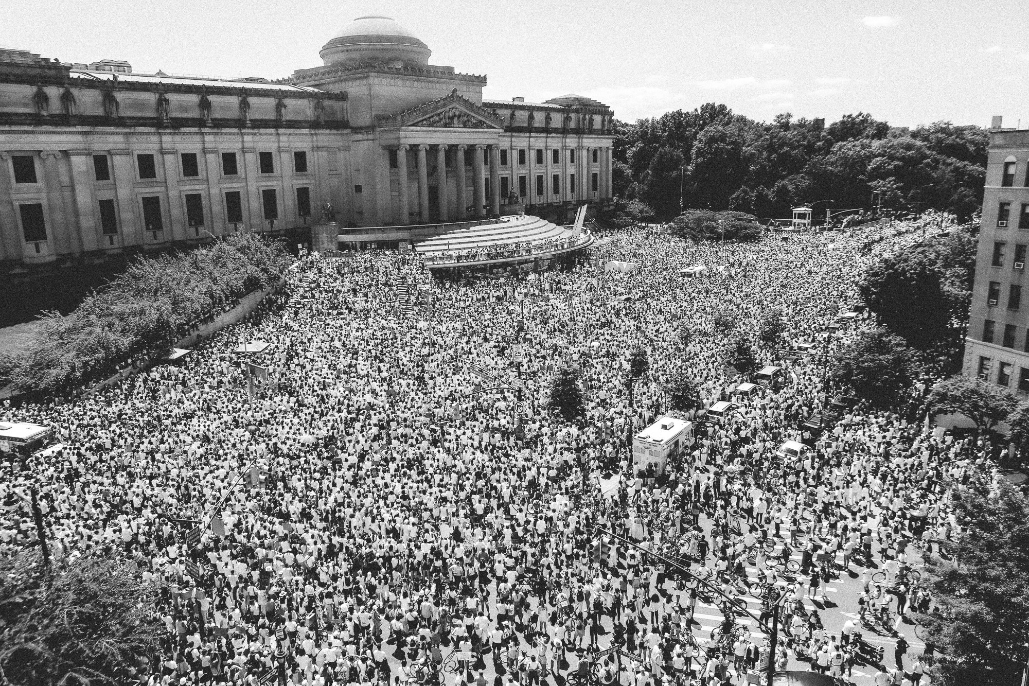 An overhead view of a huge group of protestors wearing white outside of the Brooklyn Museum