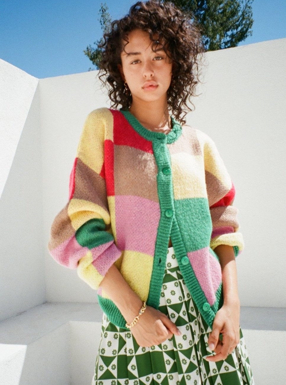 a model wearing a checkered cardigan with yellow, tan, pink, red, and green squares