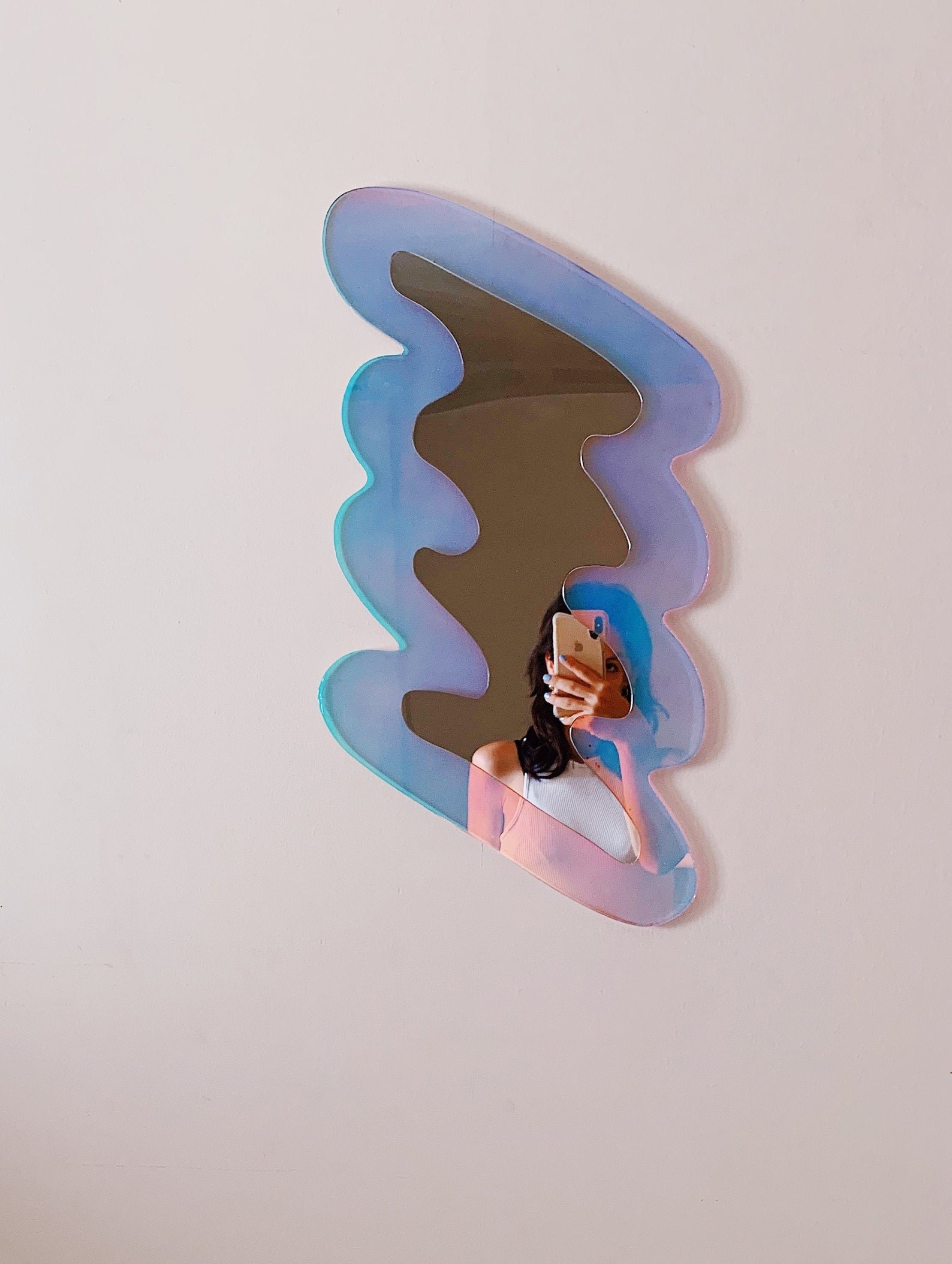 a squiggle shaped mirror with a holographic background