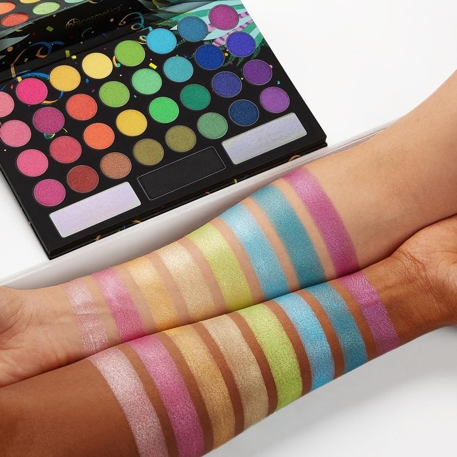 two models with eyeshadow swatches on their arms