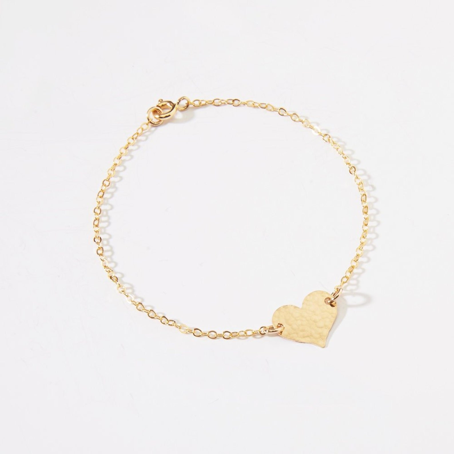 A golden bracelet with a small heart charm.