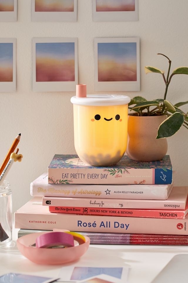 light shaped like bubble tea cup with smiling face on top of a stack of books