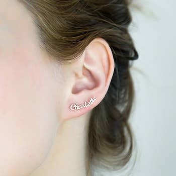 a model wearing earrings that say 