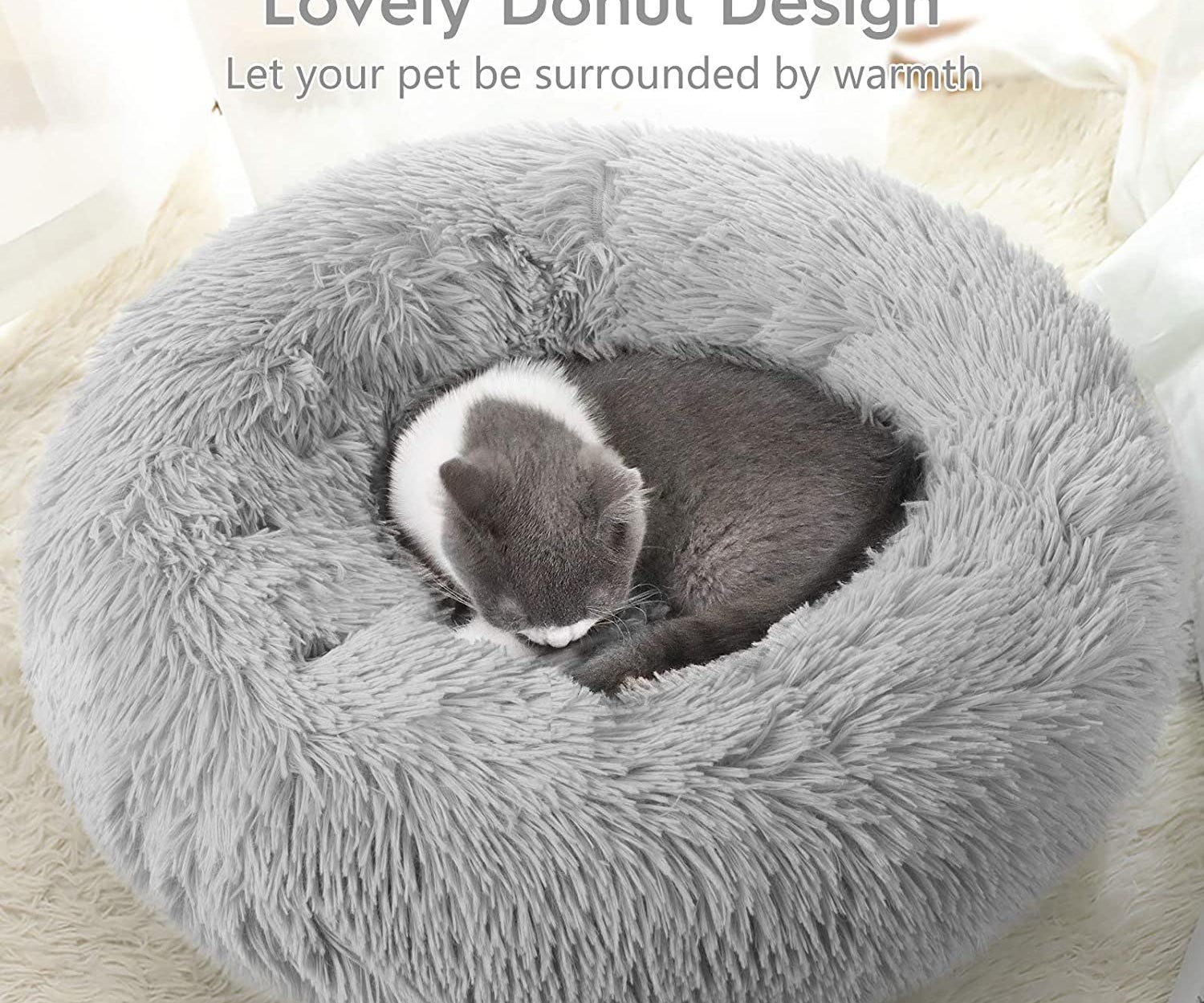 A tiny kitten curled up in the fluffy donut shaped bed
