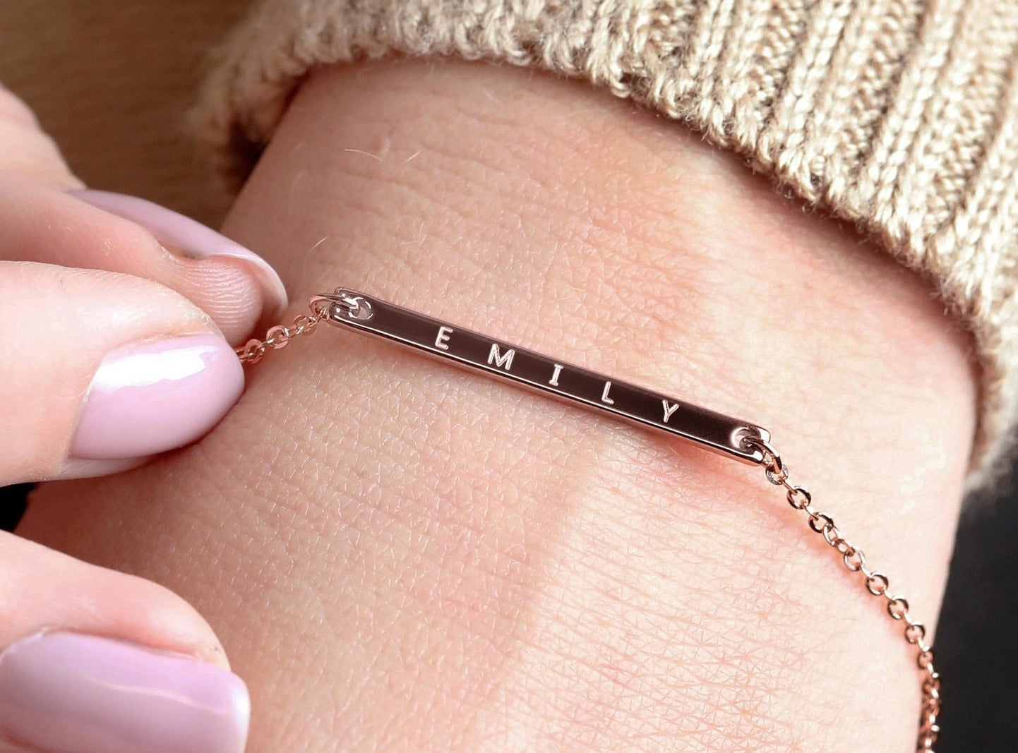 A simple golden bracelet with a bar engraved with the name &quot;Emily.&quot;