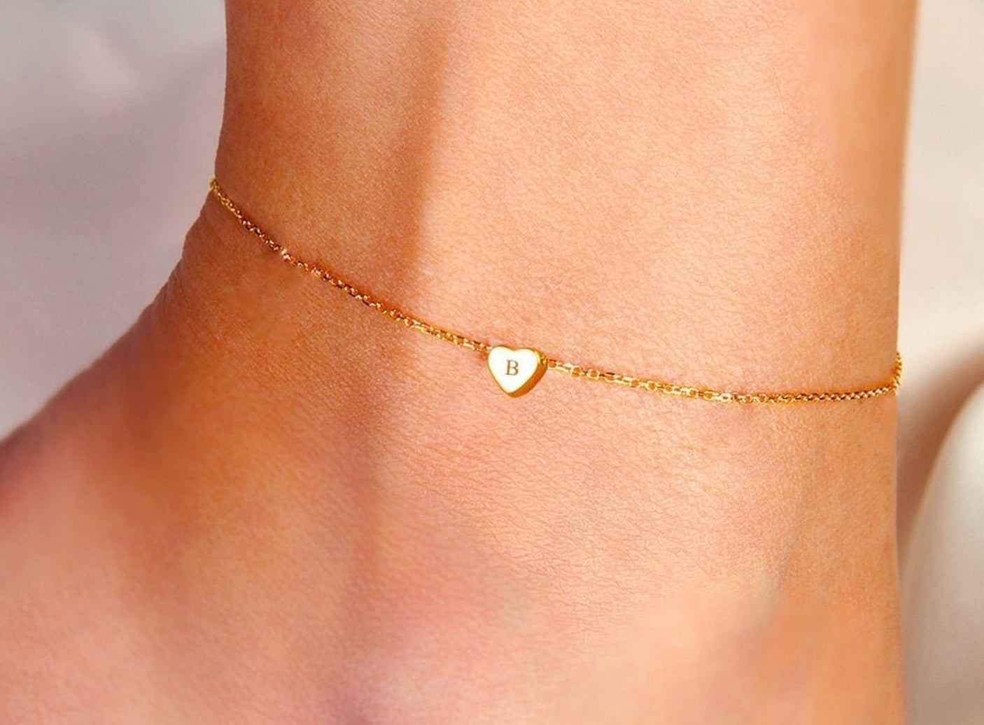A small anklet with a monogrammed heart charm.