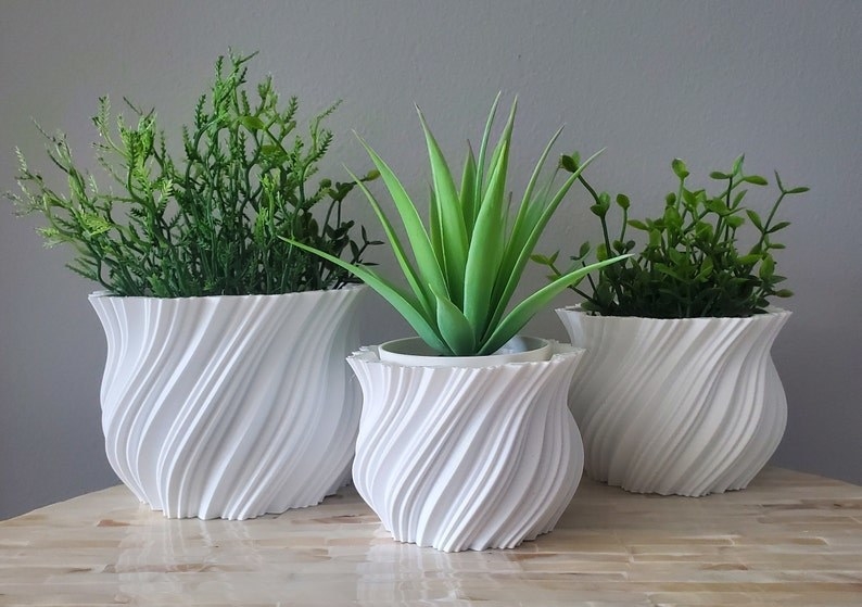 Product image of three white geometric pots filled with succulents