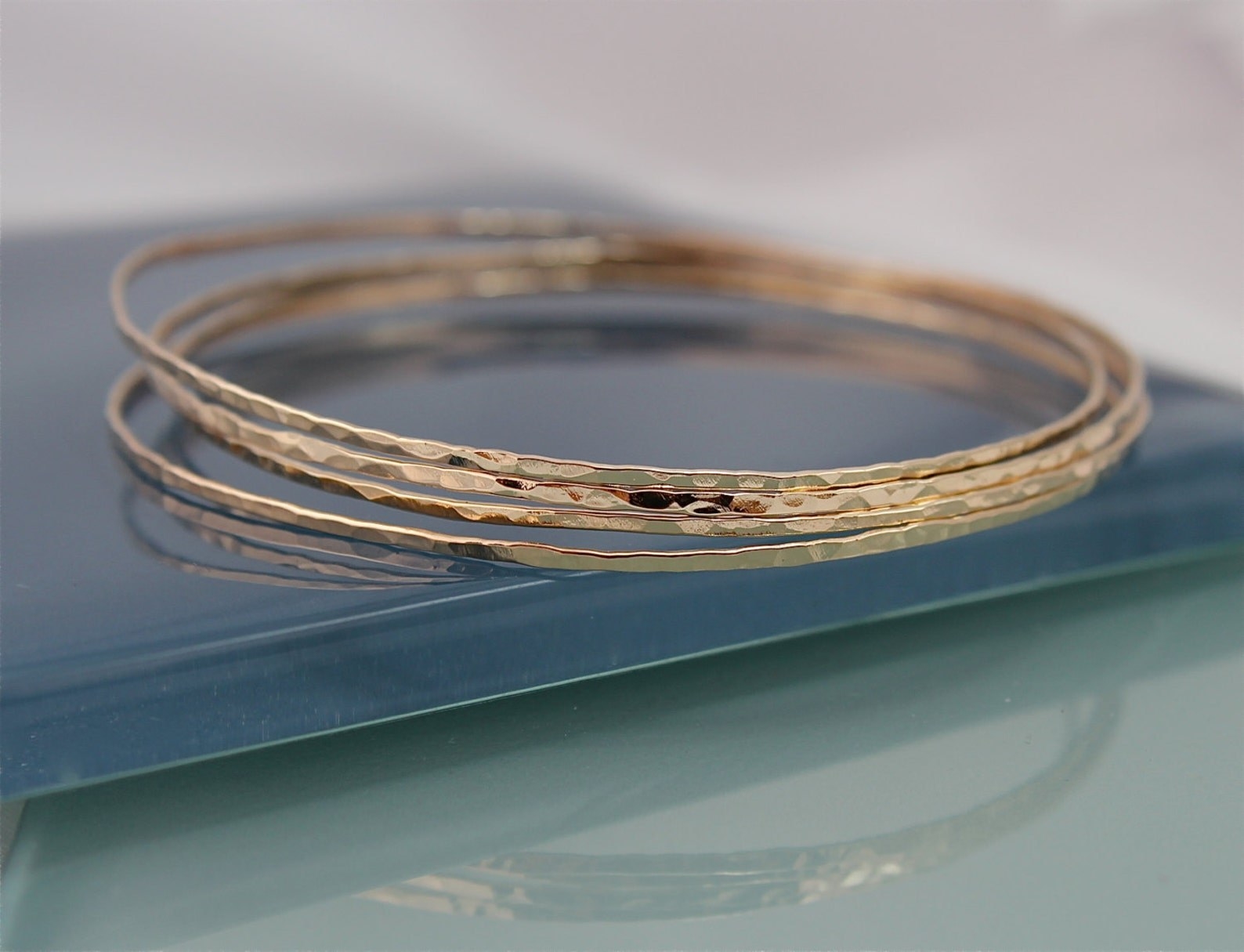 A set of four golden bangles with a hammered texture.