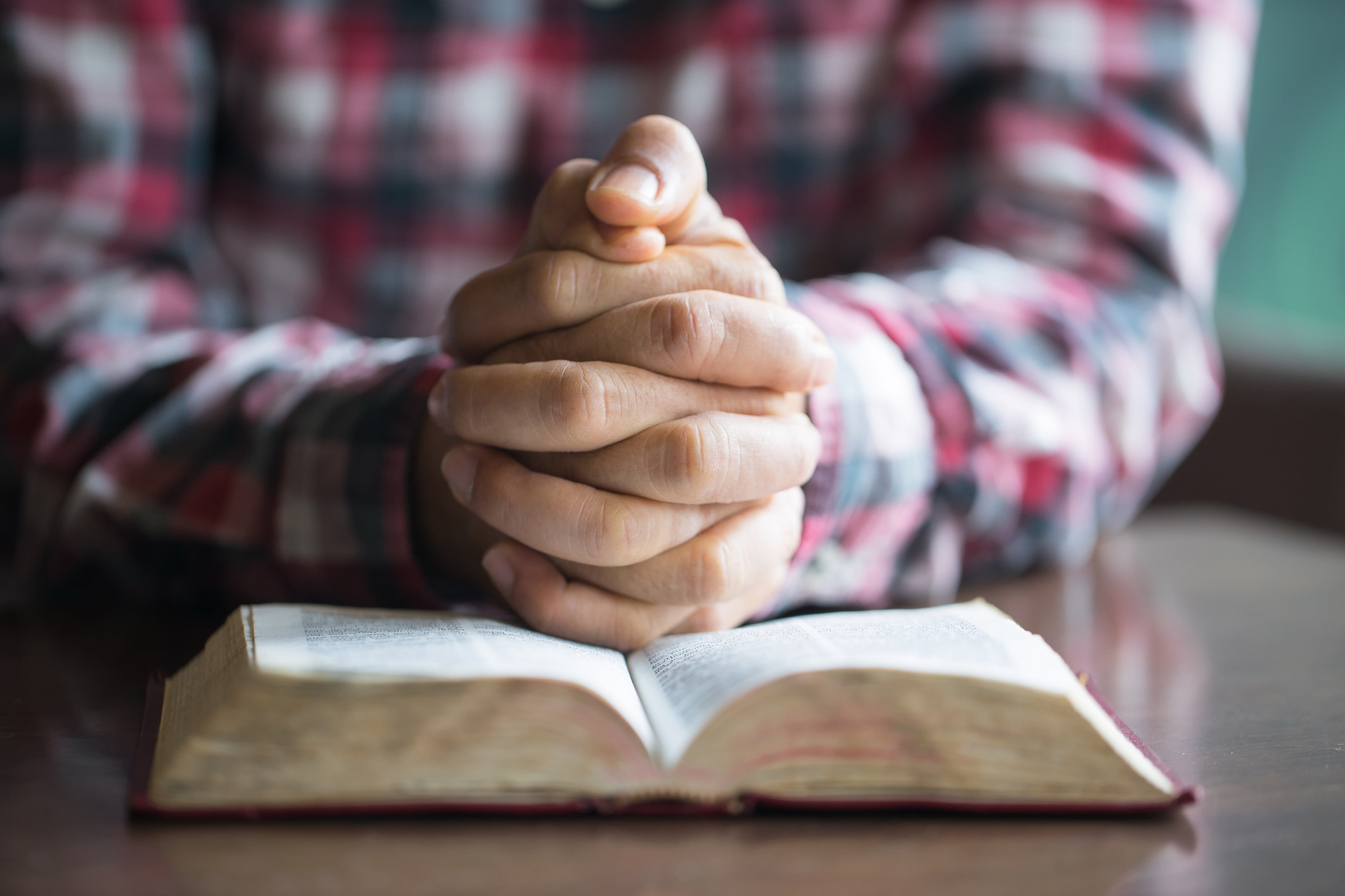 A man with his hands folded over the Bible