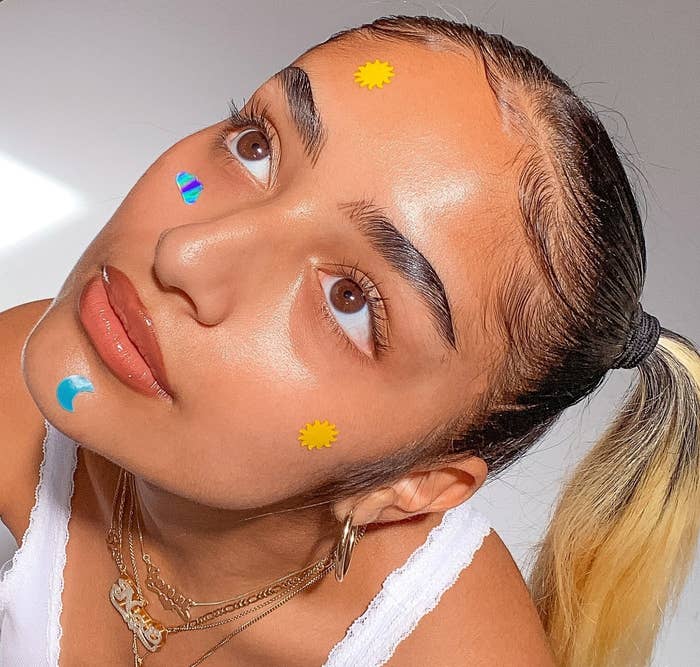 a model wearing four of the pimple patches on their face that look like a sun, a moon, a cloud, and another sun