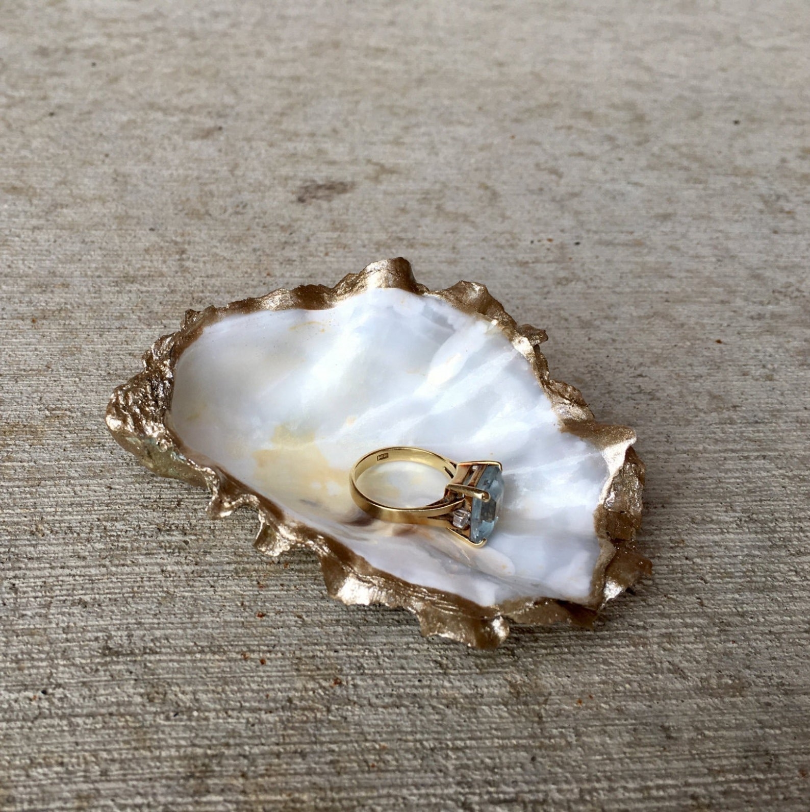 an oyster with a white interior and gold rim, holding a ring
