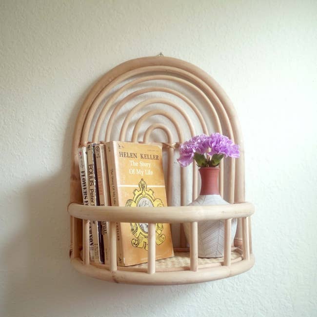 the rattan wall shelf holding books and decor