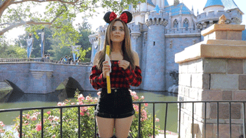 YouTuber Rosanna Pansino jumping up and down with joy at Disneyland while eating a churro