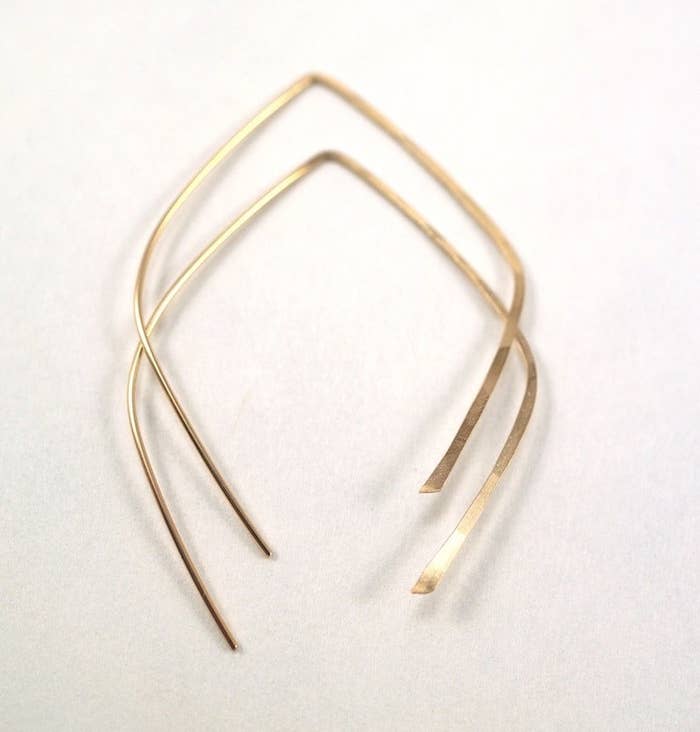 A pair of golden, teardrop-shaped hoops with open ends.
