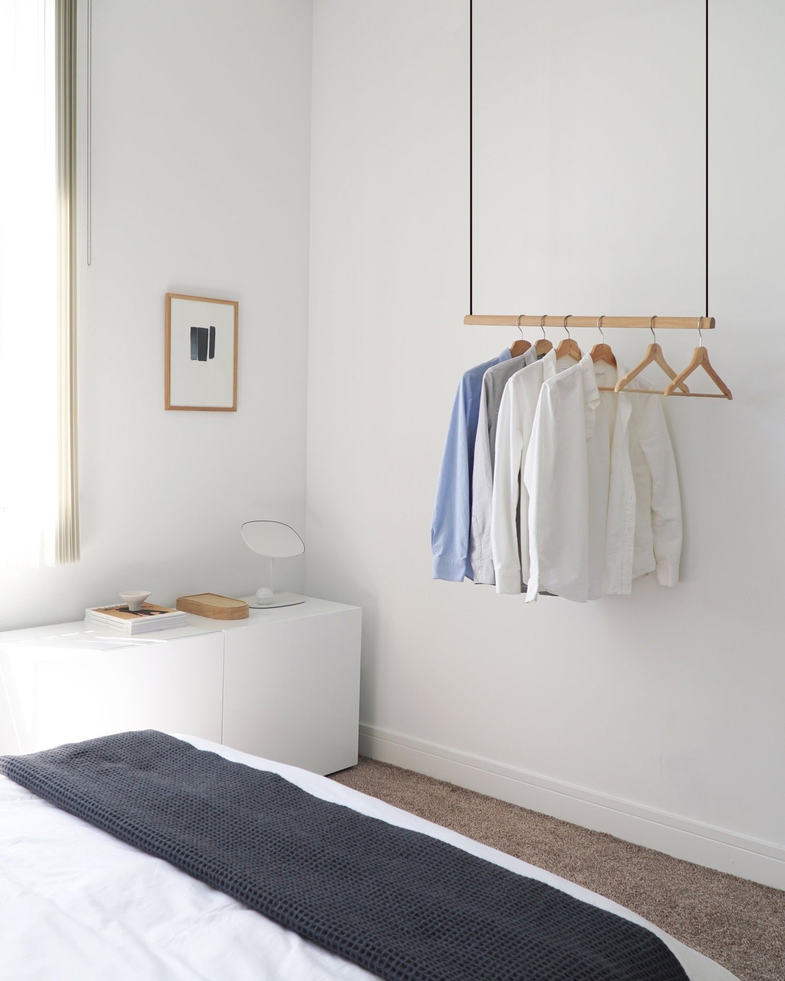 a hanging clothes rack in a bedroom holding collared shirts